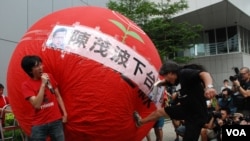 香港立法會議員梁國雄(右)腳踢巨型氣球，喻意「踢走陳茂波」 (美國之音湯惠芸拍攝)