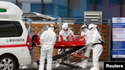 一位確診感染冠狀病毒的病人在南韓春川被推進一家醫院（2020年2月20日）。