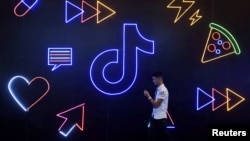 资料照：一名男子手持手持走过TikTok的标识。（2019年10月18日）
