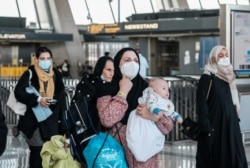 阿富汗难民抵达华盛顿附近的杜勒斯国际机场后登上接送他们前往受理中心的巴士。(2021年8月28日)