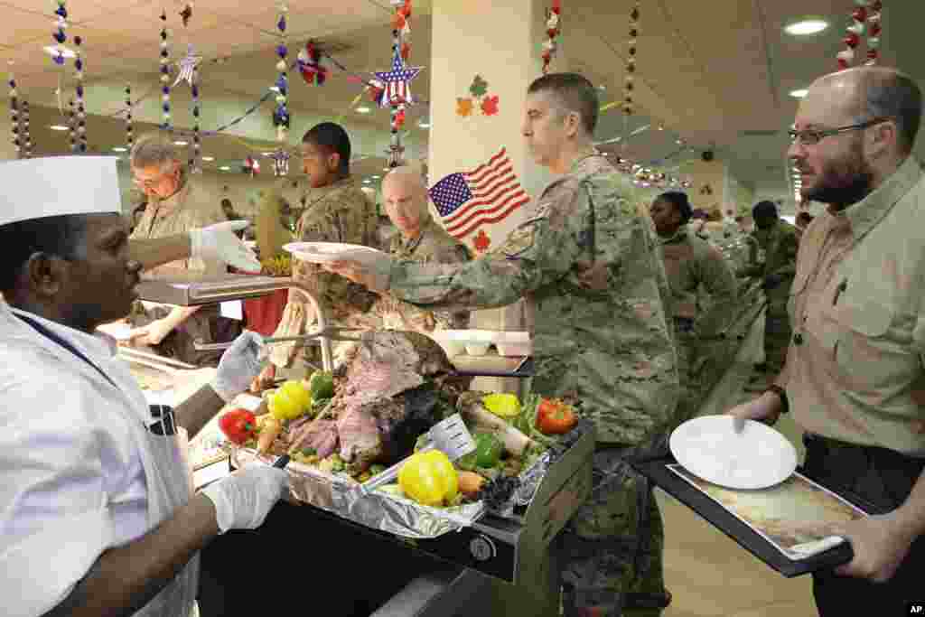 2012年11月22日，感恩节大餐开饭时间到了，一位餐厅员工（左）在以美国为主导的联军驻阿富汗喀布尔的基地为军人和文职人员服务。