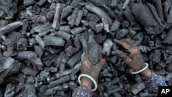 ແມ່​ຍິງ​ຄົນ​ນຶ່ງ​ເຮັດ​ວຽກ​ຢູ່ບ່ອນເກັບ​ຖ່ານ​ຫີນ​ແຫ່ງ​ນຶ່ງ​ໃນ​ເມືອງ ອາເມດາບາດ (Ahmedabad) ປະ​ເທດ​ອິນ​ເດຍ.