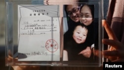 中國維權律師王全璋的妻子李文足手舉全家福照片和天津警方的逮捕通知書。（2018年12月17日）