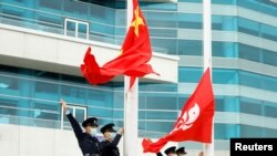 2021年3月11日，在中國香港金紫荊廣場舉行的升旗儀式上，警察在中國和香港的旗幟旁做手勢。