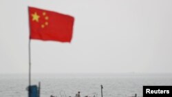 石油洩漏事故後，山東青島港飄揚的國旗下有一艘漁船。 （2021年4月28日）