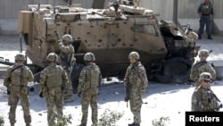 北約軍事使命團的士兵站在阿富汗喀布爾發生的自殺式汽車炸彈爆炸現場旁(資料照片)