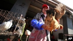 4月2 日在中國上海的一個市場一名商販用手拿著一隻雞叫買。