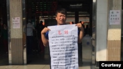 從中國大陸到台灣申請政治庇護的張文手持乞討說明。（溫起鋒提供） 