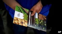 一位中國訪客在上海國際大豆展上手握一家美國大豆公司的傳單。(2018年4月12日) 