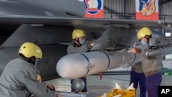 台灣嘉義一個空軍基地的地勤人員在一架F-16戰機的機翼上安裝飛彈。 （2023年1月6日）