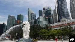 资料照片： 2020年6月30日，人们在新加坡滨海湾地区拍摄鱼尾狮雕像。