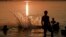 FILE - Youngsters jump into a lake as the sun sets in Bucharest, Romania, July 29, 2015, as the country battled a heat wave with temperatures reaching 39 degrees Celsius or 102.2 Fahrenheit. 