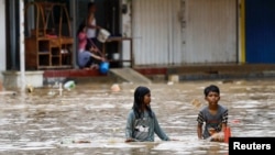 Children wade through water in a flooded residential area following heavy rains in Bekasi, on the outskirts of Jakarta, Indonesia, March 4, 2025.