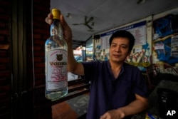 ເດືອງ ດຶກ ໂຕນ ຜູ້ຈັດການຂອງບ້ານພັກ Nana Backpacker Hostel ຍົກແກ້ວເຫຼົ້າວອດກ້າ ທີ່ຜະລິດໃນລາວ ໃຫ້ນັກຂ່າວຂອງເອພີ ຖ່າຍຮູບ ເມື່ອວັນທີ 19 ພະຈິກ 2024.