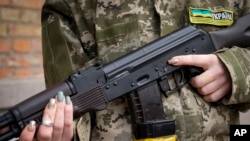 一名武裝民防婦女手持卡拉什尼科夫突擊步槍在烏克蘭基輔因宵禁而空蕩蕩的街道上巡邏。（2022年2月27日）