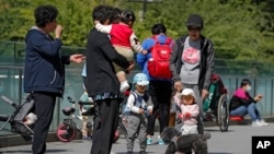 北京市民带着孩子在一处商业大楼广场上游玩 （美联社 2021年5月10日）