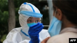 （资料照）大连一名医务工作者正在给一妇女进行核酸检测。（美联社照）