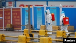 资料照片：世卫组织专家组在中国调查新冠病毒溯源期间工人在武汉白沙洲商场喷洒消毒液。（2021年1月31日） 