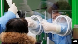 韓國醫護人員在首爾給民眾做新冠病毒檢測。 （2021年12月10日）