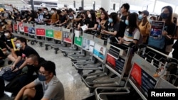 在香港機場，示威者們站在由手推車組成的路障前示威。 (2019年8月13日)