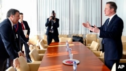 英國首相卡梅倫（右）2月19日在歐盟峰會暫停期間同意大利總理交談。