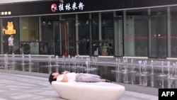 资料照：一名男子在北京一家商场的喷泉旁睡觉。（2024年7月18日）