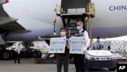 台灣疾病管制署公佈的照片顯示台灣衛生部長陳時中與美國在台協會駐台北辦事處處長酈英傑舉著感謝標語牌歡迎運載新冠疫苗的華航飛機抵達台北。(2021年6月20日)