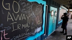 在一間已經關閉的餐館門口的黑板上，寫著希望颶風離開的文字。