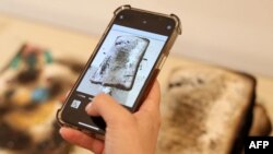 A visitor takes a picture of damaged books of the Kharkiv publishing house, which were destroyed by Russian shelling on May 23, during the opening of the annual publisher's forum "Book Arsenal" in Kyiv, on May 30, 2024.