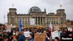 资料照片：在德国柏林的联邦议会大厦前，示威者举着“我们是人民”的标语，抗议基督教民主联盟党领袖兼总理候选人弗里德里希·梅尔茨和极右翼德国选择党的移民计划。(2025年2月2日)