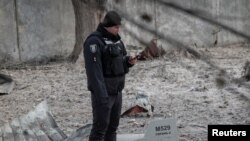 Украинский военный на фоне обломков сбитых российских дронов. Киев, 14 декабря 2022 г. 