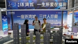 中國廣東省深圳市一個房地產博覽會的推銷員正在向客戶介紹樓型。 （2024年10月12日）