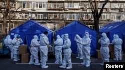 在有新冠病毒陽性民眾居家隔離的北京某居民樓外，穿著白色防護服的防疫人員集合，開始他們的執勤班次。(2022年12月8日)