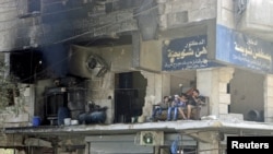 2015年8月叙利亚居民坐在被破坏的建筑物的阳台上。