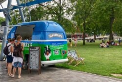 Women cool off with ice cream at La Villette park, in Paris, France. (L. Bryant/VOA)