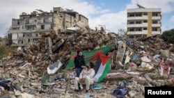 以色列和真主黨停火第二天，一對青年坐在黎巴嫩南部城鎮納巴蒂耶的一棟建築的廢墟旁，他們的家人在這棟建築裡開了一家商店。 （2024年11月28日）