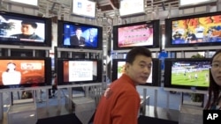 资料照：在2006年北京国际广播电影电视设备展上，一位男士站在一系列电视机前。