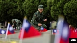 一名台灣軍人在金門古寧頭戰役75週年紀念儀式上為公共墓地的一座墳墓上香。 (2024年10月25日)