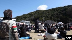 ພວກຜູ້ໄປຊົມການຍິງຈະຫຼວດ ພາກັນແນມເຫັນຄວັນ ຝຸ່ງຂຶ້ນສູ່ທ້ອງຟ້າ ຢູ່ດ້ານຫຼັງພູພາຍຫຼັງຈາກຈະຫຼວດຂະໜາດນ້ອຍຜະລິດໂດຍ ບໍລິສັດເລີ້ມຕົນໃໝ່ Space One ທີ່ມີຫ້ອງການຕັ້ງຢູ່ໃນນະຄອນຫຼວງໂຕກຽວ ໄດ້ລະເບີດຂຶ້ນບໍ່ດົນຫຼັງຈາກໄດ້ຍິງຂຶນ, ຢູ່ທີ່ Spaceport Kili ໃນເຂດຄູຊີໂມໂຕະ, ແຂວງວາກະຢາມະ, ວັນທີ 13 ມີນາ 2024.