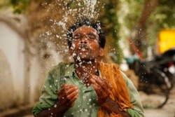 A worker splashes water to cool himself off on a hot summer afternoon in Prayagraj, Uttar Pradesh, India, June 13, 2019.