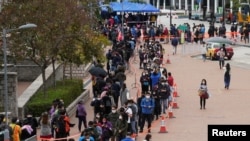 2022 年 2 月 8 日，在香港中區，市民戴著口罩在一個臨時的露天新冠病毒核酸檢測中心排隊 （路透社照片） 