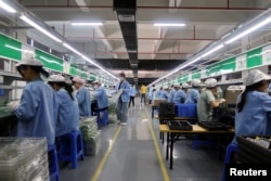 中國廣東東莞一家生產移動遊戲控制器的工廠工人在生產線上工作。（2021年12月7日）