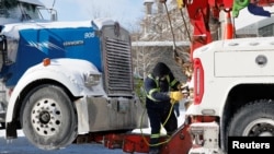 在渥太华，一位男士准备把一辆参加抗议疫苗强制令活动的卡车拖走。(2022年2月18日)