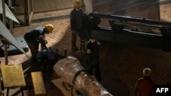 在香港大學，工人移除丹麥藝術家高志活紀念1989年天安門鎮壓事件受害者的雕塑“國殤之柱”的一部分，搬往一座集裝箱。(2021年12月23日)