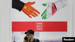 2019 年5 月28 日，在中國北京舉行的中國國際服務貿易博覽會上，一名男子在一張寫著“中國在佛羅倫薩遇見歐洲”的海報旁邊接聽電話。