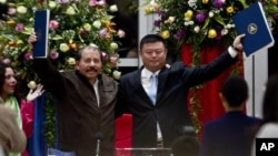 资料图片：在这种2013年6月14日的资料照片中，尼加拉瓜总统丹尼尔·奥尔特加和中国商人王靖在首都马那瓜的Casa de los Pueblos举起一份价值数十亿美元的运河建设特许权协议。2014年1月8日，获得建设和运营横跨尼加拉瓜的跨洋运河特许权的中国公司表示，该项目将为2.5万名尼加拉瓜人和2.5万名外国人创造就业机会。