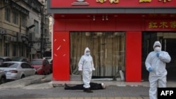 身穿防護服的中國衛生官員在檢查一名在武漢一所醫院附近倒地死亡的老年男子。（2020年1月30日）