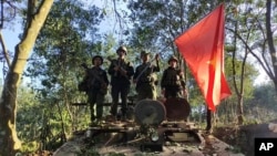 緬甸民族民主同盟軍成員在被查獲的一輛緬甸陸軍裝甲車上舉旗合影。（2023年10月28日）