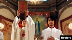 資料照： 北京天主教堂裡的一名神職人員在做聖誕彌撒時高舉中文版的聖經。 （2007年12月24日）