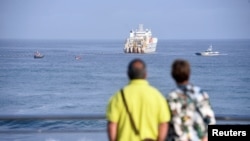 2017年6月13日，西班牙北部毕尔巴鄂附近的阿里塔拉（Arrietara）海滩，一对夫妇在观望海上的电缆铺设船。